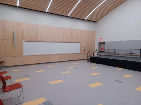 A large empty space with a stage to the side and a large white board front and center